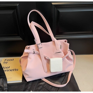 Dettaglio della borsa tote in ecopelle rosa con mini ciondolo bianco e fibbie laterali