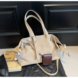Dettaglio della borsa tote beige con pieghe in pelle morbida e cartellino marrone