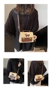 Detail of crossbody bag featuring contrast colors and dachshund embroidery with plush charm
