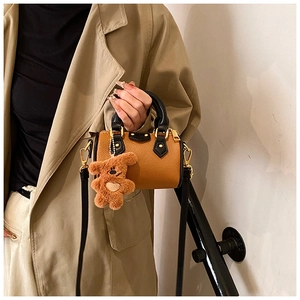Mini sac Boston marron avec breloque ours et bandoulière porté par un mannequin