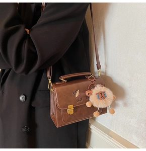 Detail of vintage brown PU leather crossbody bag with dachshund embroidery and plush charm