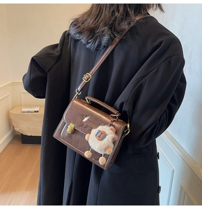 Detail showing brown leather crossbody bag with dachshund print and plush sheep charm