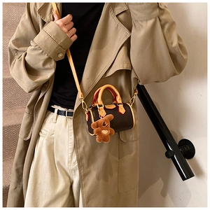 Détail du mini sac Boston avec finition rouge et charmant petit ours en peluche