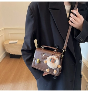 Close-up of brown vintage square bag with cute dog embroidery and fluffy charm detail