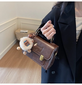 Detail of a brown vintage tote bag with puppy embroidery and a plush ball keychain charm