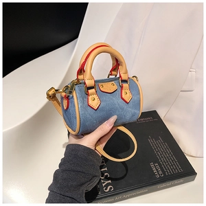 Détail du mini sac boston en jean avec poignées en cuir marron et finitions dorées