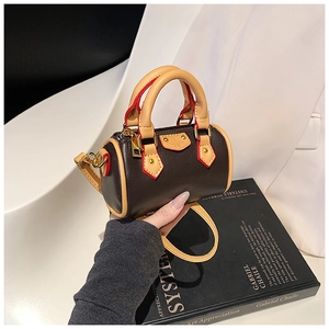 Détails d'un mini sac polochon en cuir marron foncé avec finition de peinture rouge