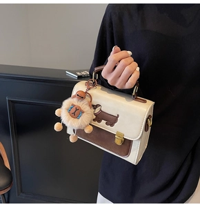 Detail of contrast stitching, dachshund embroidery, and plush charm on the square handbag