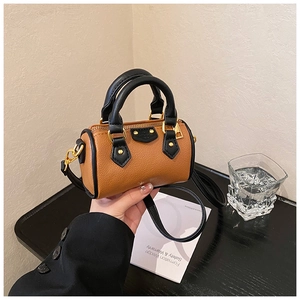 Détail du mini sac polochon en cuir marron avec poignées noires et finitions dorées