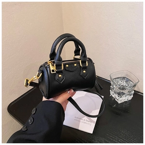 Gros plan d'un mini sac oreiller noir grainé avec ferrures dorées et doubles poignées