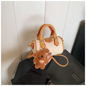 Détail du mini sac Boston blanc cassé avec poignées brunes et charme petit ours