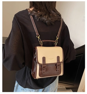 Close-up of contrast leather backpack showing gold fashion logo and strap details