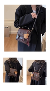 Detail view of brown messenger bag with plush bear charm and plaid scarf accessory