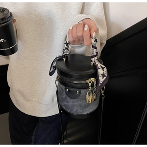 Detail of cylinder bucket bag with scarf-wrapped handle and golden padlock charms