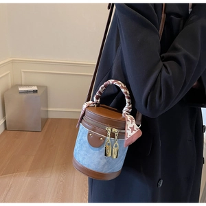 Model wearing a denim and brown leather cylinder bucket bag with houndstooth silk scarf
