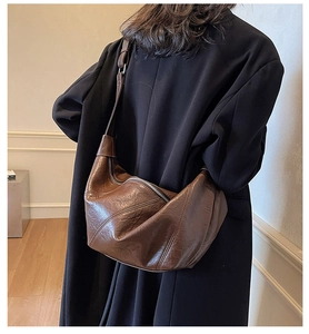 Close-up of a vintage brown leather dumpling bag with soft pleats and glossy finish