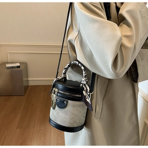 Detail of cylinder bucket bag featuring canvas patchwork and silk scarf wrapped handle