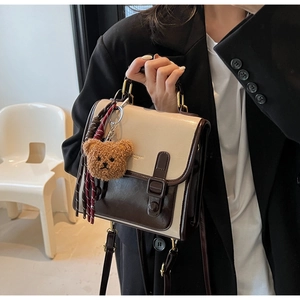 Detail of vintage contrast crossbody bag featuring a plush bear charm and metallic handle