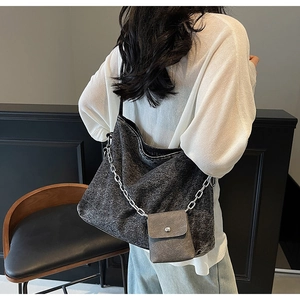 Detail view of a large dark grey denim tote bag with silver chain and a mini pouch