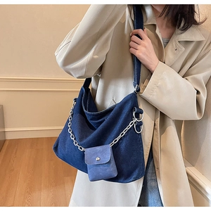 Detailed close-up of large denim hobo tote with silver chain and mini pouch on model