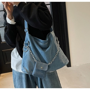 Detail of blue denim tote bag featuring chunky silver chain and mini pouch accessory