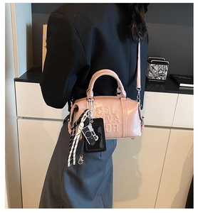 Detailed close-up of pink PU leather bowling bag with embossed letters and camera charm