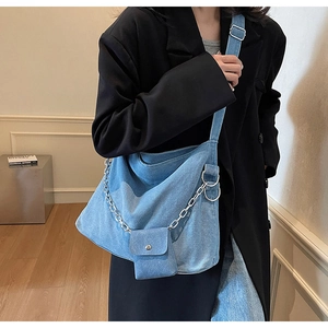 Detail view of denim hobo bag featuring a removable silver chain and mini coin pouch