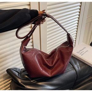 Detail view of burgundy crescent dumpling bag with retro pleated faux leather texture