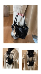 Détail d'un sac à main noir à motif marbré avec ferrures dorées et breloque en peluche