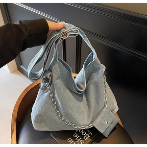 Detail of light blue denim tote bag featuring silver chain and mini matching coin purse