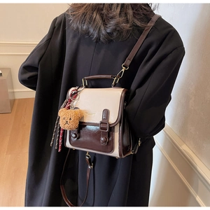 Detail of retro color-block shoulder bag with plush bear charm and top handle strap