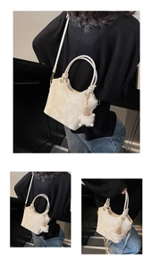 Détail d'un sac seau crème avec poignées rondes et pendentif en peluche doux