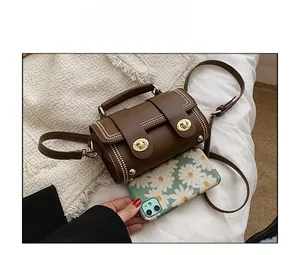 Retro brown contrast handbag with golden twist lock and rivets compared to a phone size
