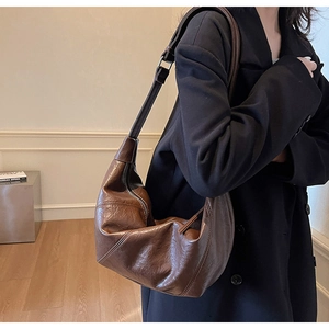 Detail of dark brown vintage dumpling bag with lychee texture and smooth top zipper