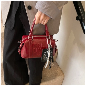 Detail of red vintage Boston bag featuring embossed Cultiva lettering and silver hardware