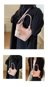 Détail du sac seau rose avec motif marbré, logo et charmant mouton en peluche blanche