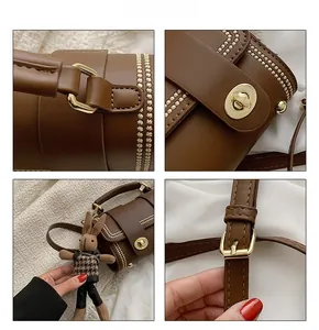 Detail of dark brown leather handbag featuring a gold twist lock and pearl bead trim