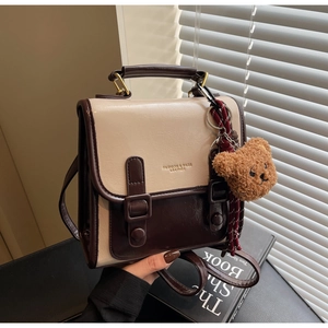 Detailed close-up of a two-tone PU leather mini backpack with a cute bear charm pendant