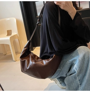 Detail of a dark brown half-moon hobo bag in oily wax faux leather with retro pleated texture