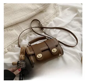 Detailed view of a brown vintage handbag with gold rivets and a cute rabbit charm