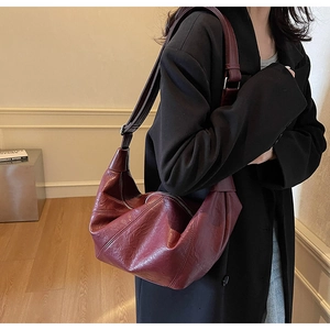 Close-up of a burgundy hobo bag featuring pleated wax texture leather and adjustable strap