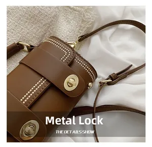 Detail of the golden oval twist lock and metal stud inlay on the vintage brown bag