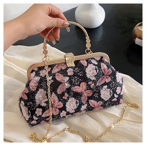 Detail einer schwarzen Sticktasche mit rosa Blumenmuster und goldenem Clipverschluss