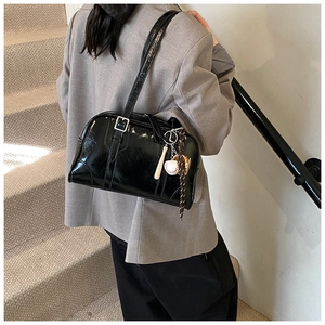 Detail of black glossy Boston bag with baseball charm and silver buckle strap