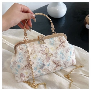 Detail der Schmetterlingsstickerei auf eleganter weißer Handtasche mit goldenem Metallgriff