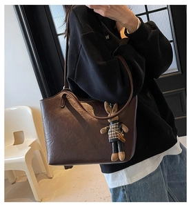 Détail d'un sac cabas en cuir marron avec logo doré et pendentif lapin élégant