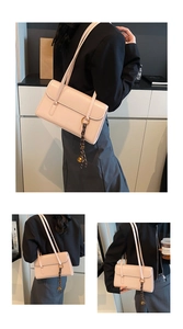 Detail of light pink oil wax leather underarm bag with gold ring and silk scarf tassel