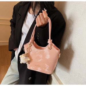 Sac seau rose avec motif marbre, poignée torsadée et détail de breloque pompon blanc