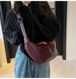Close-up of burgundy leather dumpling bag featuring soft pleats and wide shoulder strap