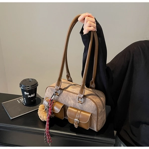 Detail of vintage brown leather Boston bag with side pockets and teddy bear charm accessory